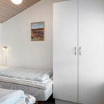 Zimmer mit zwei Betten, weißem Schrank und Wandbild