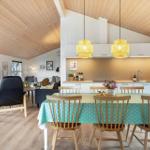 Esszimmer mit Holztisch, Stühlen und grünem Tischtuch. Küche und Wohnzimmer im Hintergrund.
