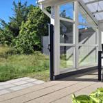 Terrasse mit Sitzgruppe, Glasfront und Blick auf grünen Garten.