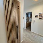 Eingangsbereich mit Holzgarderobe und Blick in die Küche.