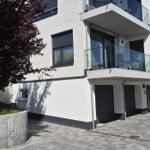 Moderne Wohnung mit Balkon und Garage. Außenbereich mit Bäumen und gepflastertem Hof.