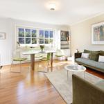 Living room with dining table, sofa, and bookcase. Wooden floor and window with view.