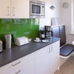 Kitchen with worktop, microwave, coffee machine, and bench by the window.