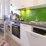 Kitchen with green backsplash, sink, stove, oven, and dishwasher.