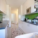 Modern kitchen with white cabinets, green backsplash, and kitchen counter.