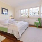 Bedroom with bed, window, and green chair corner.