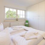 Bedroom with double bed, window, and white wardrobes.