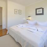 Bedroom with bed, nightstands, and pictures on the wall. Door leads to the kitchen.