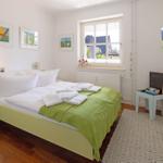 Bedroom with bed, window, TV, and decorative pictures on the wall.