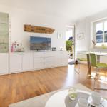 Living and dining area with wooden floor, TV, dining table, and windows.