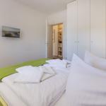 Bedroom with bed, wardrobe, and TV mounted on the wall.