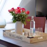 Ein Holztablett mit Rosen, Wasser und Gläsern auf einem Tisch.