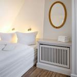 Schlafzimmer mit weißem Bett, runden Spiegel und Handtüchern.