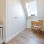 Kleines Zimmer mit Schrank, Schreibtisch und Stuhl unter Dachschrägen.