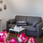 Ein Wohnbereich mit grauem Sofa, weißem Couchtisch und Wandbildern.