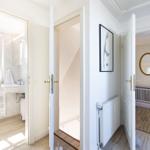 Durchgang mit Blick in Bad und Schlafzimmer. Weiße Türen, Holzboden und Wandbild.