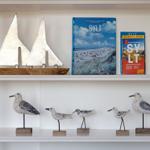 Regal mit Segelboot-Modell und Büchern über Sylt sowie Vogeldekoration.