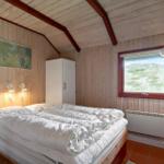 Schlafzimmer mit Holzwand, Bett, Fenster und Schrank