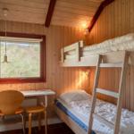 Zimmer mit Doppelstockbett, Schreibtisch und Fenster mit Blick auf Gras.