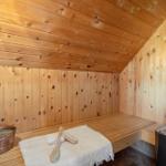 Holzsauna mit Bank, Körbchen und Bürsten. Dampfheizung und Badewanne sind vorhanden.