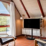 Zimmer mit Fernseher, zwei Sesseln und Blick auf Grasflächen.