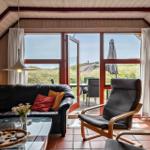 Wohnzimmer mit Sofa, Sessel und Blick auf Terrasse und Dünen.