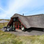 Hütte mit Strohdach und Holzterrasse im Grasland.