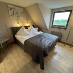 Bedroom with sloped ceiling, bed, window, and clothes rack.