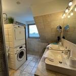 Bathroom with washing machine, mirrors, and window