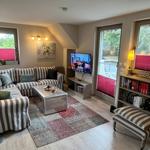 Living room with sofa, TV, and bookshelf. Windows with red blinds.