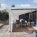 Terrasse mit Tisch, Stühlen und Pavillon neben blauem Haus mit Zugang zur Wohnung.