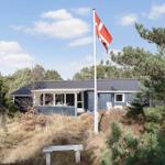 Ein blauer Holzhaus mit Flagge und Terrasse umgeben von Bäumen und Gras.