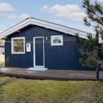 Blau gestrichenes Haus mit Holzterrasse und Fenstern. Umgeben von Gras und Bäumen.
