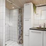 Badezimmer mit Dusche, Waschbecken und weißen Schränken.
