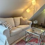 A sofa with cushions, a glass table, and floor lamps in a room with a sloped ceiling.