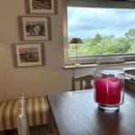 Table with candle, window view of forest, wall art, and lamp