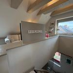 Living area with sofa, view of roof and window overlooking rooftops.