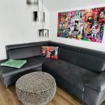 Schwarzer Ecksofa mit Kissen und runden Tisch vor Wandbild