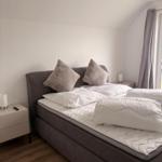 Schlafzimmer mit Doppelbett, Nachttischen und Fenster mit Vorhängen.