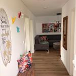 Flur mit Holzboden, Wanddekoration und Blick in Wohnzimmer mit Sofa und Wandbild.