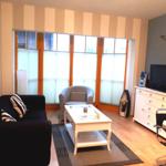 Wohnzimmer mit Sofa, Sessel, Couchtisch und Fernseher.