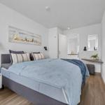 Schlafzimmer mit Bett, Wandbild, Schreibtisch und Fernseher.
