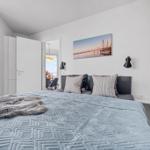 Schlafzimmer mit Bett, Wandbild und Nachttisch. Tür führt in Wohnbereich.