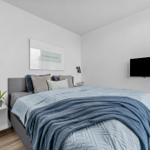 Schlafzimmer mit Bett, Wandbild und Fernseher.