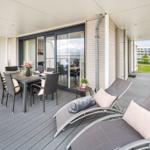 Terrasse mit Essgruppe und Liegestühlen. Blick auf Hotel und Grünfläche.