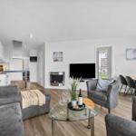 Wohnbereich mit Sofa, Sessel, Esstisch und Küche. Kamin und Fernseher im Zentrum.
