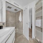 Badezimmer mit Dusche, Waschbecken und Handtuchhalter.