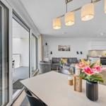 Wohnung mit Blick auf Hafen, Küche und Essbereich mit Blumen auf Tisch.