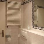 Bathroom with sink, mirror, towel radiator, and toilet paper holder.