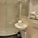 Badezimmer mit Dusche, Waschbecken und Handtüchern.